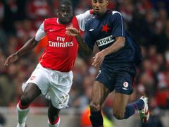 Emmanuel Eboue z Arsenalu (vlevo) bojuje o míč se slávistou Mickaelem Tavaresem.