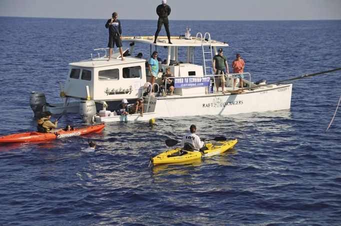 Endurance swimmer Diana Nyad (yellow bathing cap) pauses for a rest and hydration with her support crew in the Florida Straits between Cuba and the Florida Keys August 19, 2012. Nyad is trying to become the first swimmer to transit the Florida Straits from Cuba to the Keys without a shark cage. REUTERS/Christi Barli/Diana Nyad/Florida Keys News Bureau/Handout (UNITED STATES - Tags: SOCIETY) NO SALES. NO ARCHIVES. FOR EDITORIAL USE ONLY. NOT FOR SALE FOR MARKETING OR ADVERTISING CAMPAIGNS. THIS IMAGE HAS BEEN SUPPLIED BY A THIRD PARTY. IT IS DISTRIBUTED, EXACTLY AS RECEIVED BY REUTERS, AS A SERVICE TO CLIENTS Published: Srp. 19, 2012, 11:32 odp.