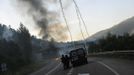 Spanish national riot police take cover behind a police van after firing tear gas canisters during a clash with coal miners in the surroundings of the "El Soton" coal mine in El Entrego, near Oviedo, northern Spain June 15, 2012. The miners were protesting against the government's proposal to decrease funding for coal production. REUTERS/Eloy Alonso (SPAIN - Tags: CIVIL UNREST BUSINESS EMPLOYMENT ENERGY CRIME LAW COMMODITIES) Published: Čer. 15, 2012, 11:59 dop.