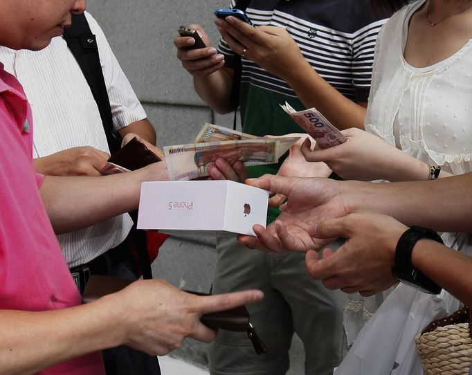 A customer (R) who just bought an iPhone 5 from an Apple store resells the newly released smartphone, to another man who is expected to ship it as parallel goods into mainland China, for at least HK$1,200 ($150) more than the original price, right after the customer left the store in Hong Kong September 21, 2012. Apple Inc's iPhone 5 hit stores around the globe on Friday, with fans snapping up the device that is expected to fuel a huge holiday quarter for the consumer giant. REUTERS/Bobby Yip (CHINA - Tags: BUSINESS SCIENCE TECHNOLOGY) Published: Zář. 21, 2012, 2:15 dop.