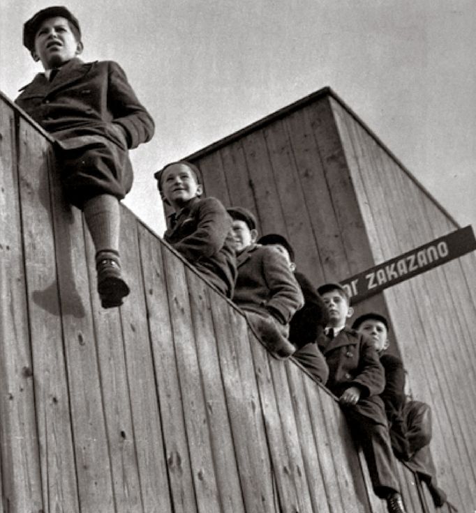 Skupina nejmenších fanoušků v listopadu 1940 z ohrady sparťanského stadionu sleduje ligový šlágr na Letné.