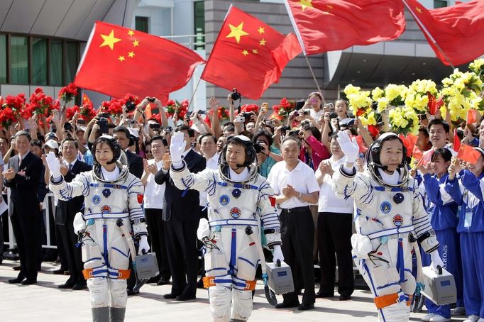 Chinese astronauts Jing Haipeng, Liu Wang (C) and Liu Yang (L), China's first female astronaut, wave during a departure ceremony at Jiuquan Satellite Launch Center, Gansu province, June 16, 2012. China will send its first woman into outer space this week, prompting a surge of national pride as the rising power takes its latest step towards putting a space station in orbit within the decade. Liu Yang, a 33-year-old fighter pilot, will join two other astronauts aboard the Shenzhou 9 spacecraft when it lifts off from a remote Gobi Desert launch site on Saturday evening. REUTERS/Jason Lee (CHINA - Tags: SCIENCE TECHNOLOGY) Published: Čer. 16, 2012, 8:13 dop.