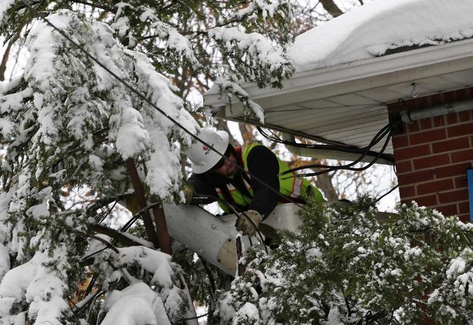 Zaměstnanec elektrárenské společnosti opravuje poškozené dráty.