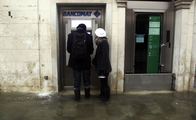 A person withdrawals money from an automated teller machine in a flooded street during a period of seasonal high water in Venice November 1, 2012. The water level in the canal city rose to 140 cm (55 inches) above normal, according to the monitoring institute. REUTERS/Manuel Silvestri (ITALY - Tags: ENVIRONMENT SOCIETY TRAVEL) Published: Lis. 1, 2012, 12:59 odp.