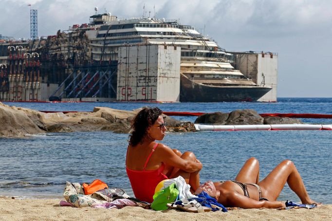 People sunbathe as the Costa Concordia cruise liner is seen during its refloating operation at Giglio harbour July 21, 2014.