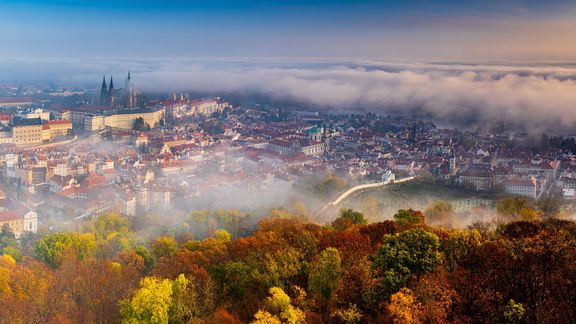 Praha podzimní z nadhledu s mlhou v pozadí 