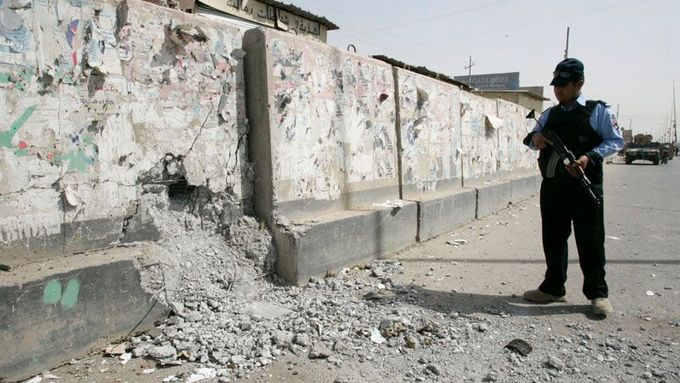 Irácký policista hlídkuje u zdi poničené výbuchem v Sadrově městě. Bagdád, 9. července