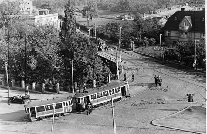 Pohled z nadhledu, který celistvým způsobem ukazuje dějiště atentátu na Reinharda Heydricha. Policejní fotografie je opět vybavena poznámkami německých vyšetřovatelů.