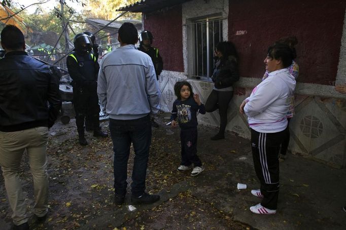 Five-year-old Moises Echevarria (C) looks at his family as Spanish riot police prevent them from approaching a bulldozer that is demolishing their living-room at the Spanish gypsy settlement of Puerta de Hierro outside Madrid November 8, 2011. Fifty-four families have been living in Puerta de Hierro, on the banks of the Manzanares river for over 50 years. Since the summer of 2010, the community has been subject to evictions on the grounds that the dwellings are illegal. Families whose houses have been demolished, move in with relatives whose houses still remain while the debris keeps piling up around them as more demolitions take place. Picture taken November 8, 2011. REUTERS/Susana Vera (SPAIN - Tags: SOCIETY) ATTENTION EDITORS - PICTURE 15 OF 31 FOR PACKAGE 'GYPSY SITE DEMOLISHED' SEARCH 'GYPSY SITE' FOR ALL IMAGES Published: Lis. 5, 2012, 4:11 odp.