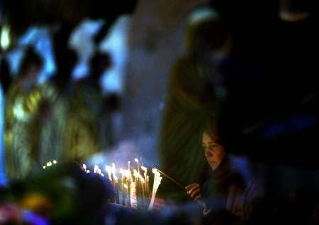 Křesťanská poutnice zapaluje svíčku uvnitř Chrámu narození Páně v Betlémě