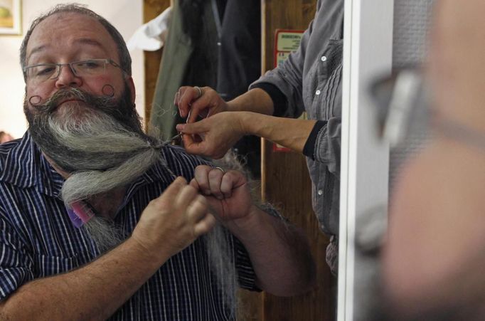 German hairdresser Elmar Weisser, 48, is reflected in a mirror in his hotel room as he starts shaping his beard as a stork, with help from his wife, to compete in the 2012 European Beard and Moustache Championships in Wittersdorf near Mulhouse, Eastern France, September 22, 2012. Weisser, who won the World Beard and Moustache Championship in 2011, ranked second in the freestyle category of the European championships on Saturday. Picture taken September 22, 2012. REUTERS/Vincent Kessler (FRANCE - Tags: SOCIETY) Published: Zář. 23, 2012, 11:52 dop.