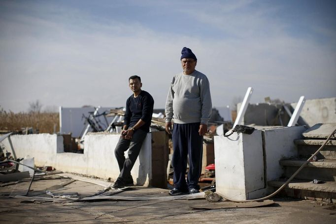 Kulib Abass, a New York City Cab driver, poses for a photograph with his son Hassan in the remains of his house on Kissam Avenue, Staten Island November 12, 2012. Abass's house was destroyed, along with most of the neighbourhood, by Hurricane Sandy. Just three years earlier, neighbours on this tight-knit seaside road had pulled together to survive a devastating Easter 2009 fire that damaged many of their homes. Most are now suddenly homeless like Abbas who said he would likely not return to rebuild on this low-lying part of Staten Island where he had hoped to spend his retirement years living by the shore. Picture taken November 12, 2012. REUTERS/Mike Segar (UNITED STATES - Tags: DISASTER ENVIRONMENT) ATTENTION EDITORS PICTURE 08 OF 19 FOR PACKAGE 'SURVIVING SANDY' SEARCH 'SEGAR SANDY' FOR ALL PICTURES Published: Lis. 20, 2012, 3:30 odp.