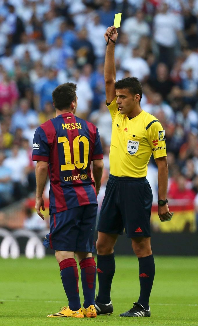 Barcelona's Lionel Messi (L) is shown a yellow card by referee Gil Manzano during the Spanish first division &quot;Clasico&quot; soccer match against Real Madrid at the S