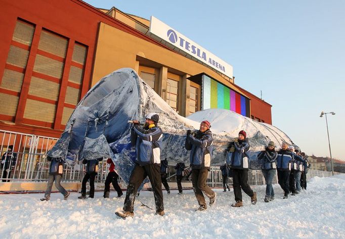 Dobrovolníci přenášejí velký modrý stan, který je k výrobě sněhu pomocí tekutého dusíku nezbytný. Tímto způsobem lze vyrobit až 50 metrů krychlových sněhu za hodinu.