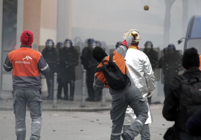 An Arcelor Mittal employee throws a stone at French riot police during a demonstration next to the European Parliament in Strasbourg, February 6, 2013. ArcelorMittal, the world's largest steel producer, plans to shut a coke plant and six finishing lines at its site in Liege, Belgium, affecting 1,300 employees. REUTERS/Jean Marc Loos (FRANCE - Tags: BUSINESS EMPLOYMENT POLITICS CIVIL UNREST) Published: Úno. 6, 2013, 5:06 odp.