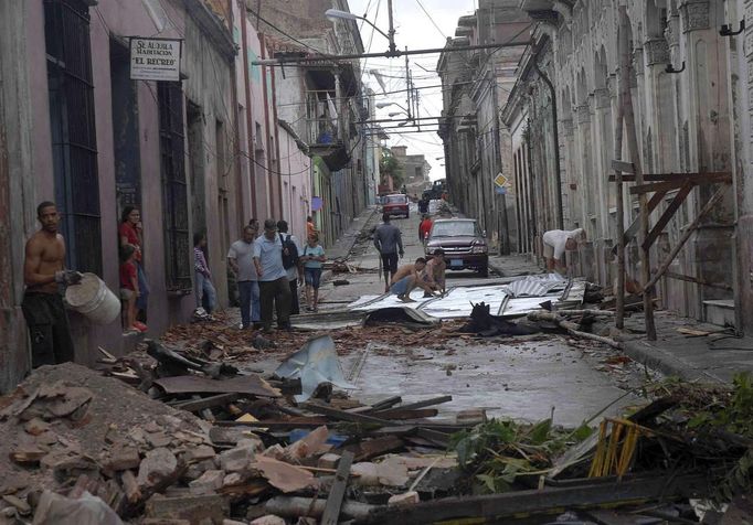 People walk near to a damaged building in Santiago de Cuba October 25, 2012. Hurricane Sandy grew into a major potential threat to the east coast of the United States on Thursday after hammering Cuba's second-largest city and taking aim at the Bahamas, U.S. forecasters said. Strengthening rapidly after tearing into Jamaica and crossing the warm Caribbean Sea, Sandy hit southeastern Cuba early on Thursday with 105-mph winds that cut power and blew over trees across the city of Santiago de Cuba. Reports from the city of 500,000 people, about 470 miles (750 km) southeast of Havana spoke of significant damage, with many homes damaged or destroyed. According to one Cuban radio report, at least one person was killed, bringing the death toll to at least three after fatalities in Jamaica and Haiti. REUTERS/Miguel Rubiera/Cuban Government National Information Agency - AIN/Handout (CUBA - Tags: ENVIRONMENT DISASTER) FOR EDITORIAL USE ONLY. NOT FOR SALE FOR MARKETING OR ADVERTISING CAMPAIGNS. THIS IMAGE HAS BEEN SUPPLIED BY A THIRD PARTY. IT IS DISTRIBUTED, EXACTLY AS RECEIVED BY REUTERS, AS A SERVICE TO CLIENTS Published: Říj. 25, 2012, 5:47 odp.