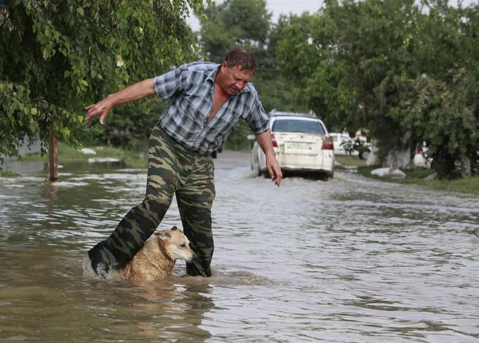 A local resident and a dog cross a flooded street in the town of Krymsk in Krasnodar region, southern Russia, July 8, 2012. Russian President Vladimir Putin ordered investigators to find out if enough was done to prevent 144 people being killed in floods in southern Russia after flying to the region to deal with the first big disaster of his new presidency. REUTERS/Eduard Korniyenko (RUSSIA - Tags: DISASTER ENVIRONMENT POLITICS ANIMALS) Published: Čec. 8, 2012, 8:06 dop.