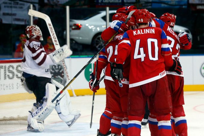 Russia's Sergei Kalinin (R) celebrates his goal against Latvia's goalie Kristers Gudlevskis (L) with team mates during the second period of their men's ice hockey World C