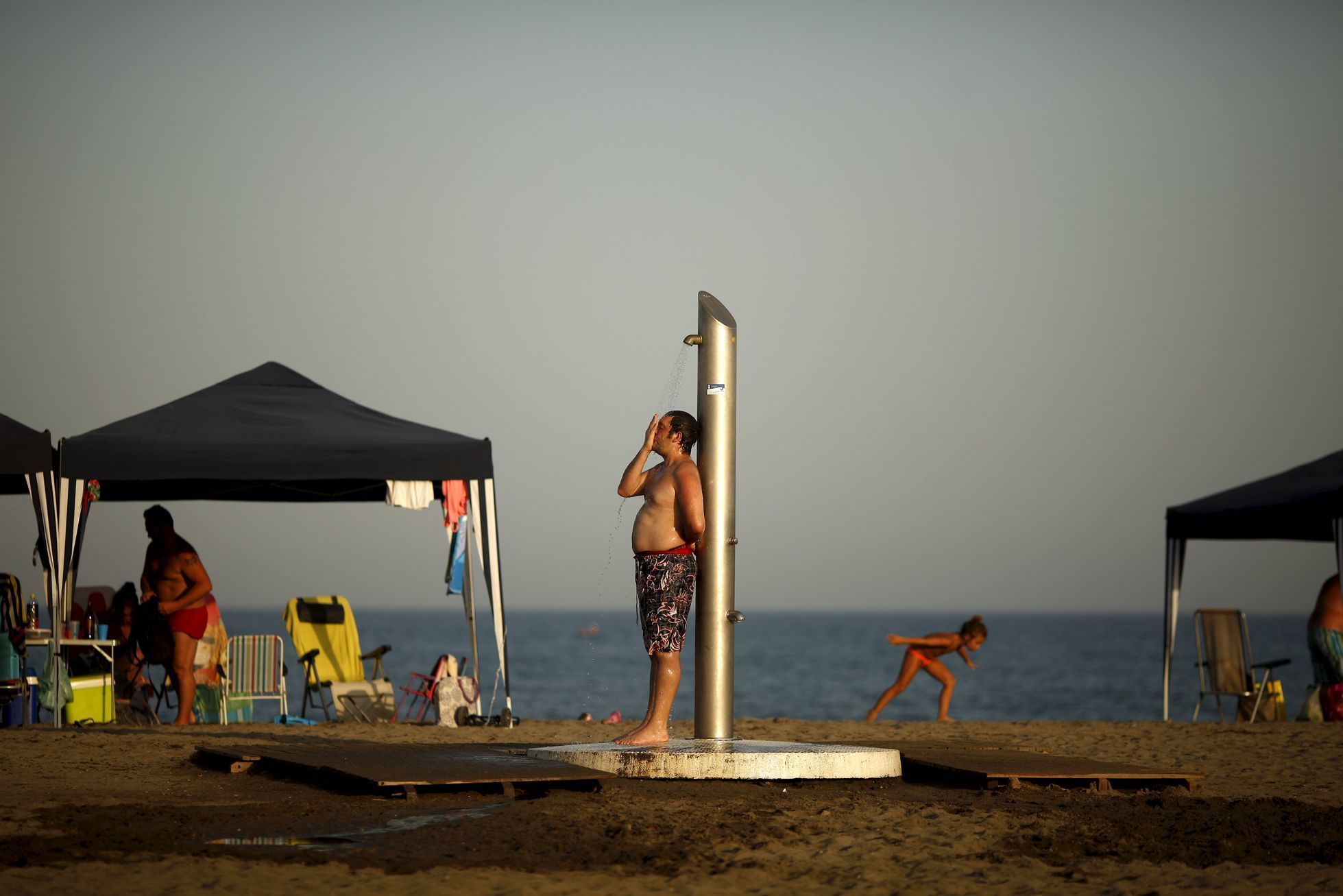 A man takes a shower during the second heat wave of the summer on Sacaba beach in Malaga