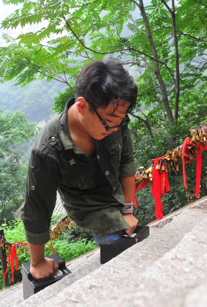 HUAYIN, CHINA - AUGUST 13: (CHINA OUT) Legless man Chen Zhou climbs the Huashan Mountain on August 13, 2012 in Huayin, Shaanxi Province of China. Legless 29-year-old man Chen Zhou from Cangshan of Shandong Province spent two days, 19 hours in total, climbing by arms to the top of Huashan Mountain. Chen lost his legs after falling off a train at the age of 13, but he has since strived to be stronger and joined in many public performances to encourage other people. Chen Zhou will climb the Taishan Mountain in Shandong province in the following months. ( automatický překlad do češtiny )