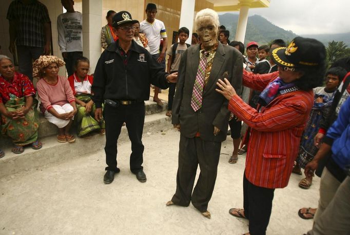 Family members hold up a mummy before giving it new clothes in a ritual in the Toraja district of Indonesia's South Sulawesi Province, August 23, 2012. The ritual, called Ma'nene, involves changing the clothes of mummified ancestors every three years to honor love for the deceased. Locals believe dead family members are still with them, even if they died hundreds of years ago, a family spokesman said. Picture taken August 23, 2012. REUTERS/Yusuf Ahmad (INDONESIA - Tags: SOCIETY RELIGION) Published: Srp. 24, 2012, 12:56 odp.