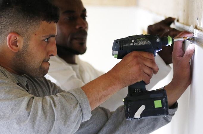 Unemployed Belgian Mohamed Sammar (L) is helped by instructor Michel Bokota as he works in a renovation site, part of the "Fit for a job" programme which includes a week-long work placement and aims to consolidate his previous work experience, in Brussels June 19, 2013. Sammar, 27, has been looking for a job in the construction sector for 2 years. "Fit for a job" is the initiative of former Belgian boxing champion Bea Diallo, whose goal was to restore the confidence of unemployed people and help them find a job through their participation in sports. Picture taken June 19, 2013. REUTERS/Francois Lenoir (BELGIUM - Tags: SPORT BOXING SOCIETY BUSINESS EMPLOYMENT) Published: Čec. 5, 2013, 4:04 odp.