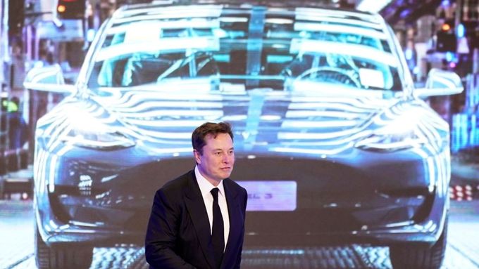 Elon Musk v pozadí se snímkem automobilu Tesla