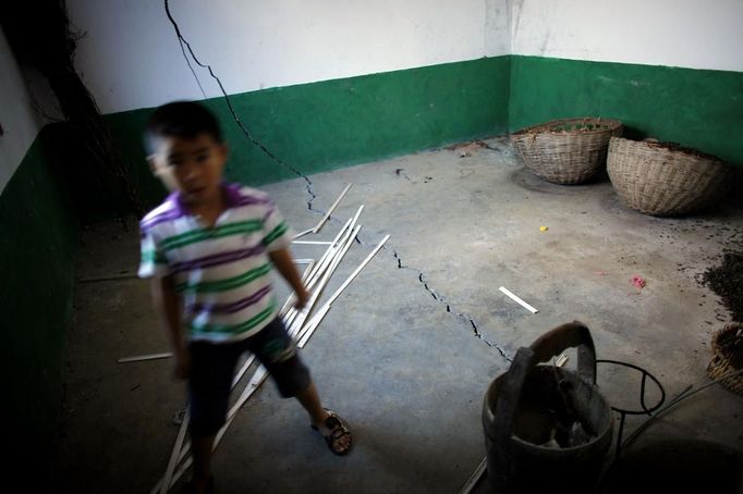 A boy stands inside a cracked house after a landslide near Badong, on the banks of the Yangtze River, 100km (62 miles) from the Three Gorges dam in Hubei province August 7, 2012. China relocated 1.3 million people during the 17 years it took to complete the Three Gorges dam. Even after finishing the $59 billion project last month, the threat of landslides along the dam's banks will force tens of thousands to move again. It's a reminder of the social and environmental challenges that have dogged the world's largest hydroelectric project. While there has been little protest among residents who will be relocated a second time, the environmental fallout over other big investments in China has become a hot-button issue ahead of a leadership transition this year. Picture taken on August 7, 2012. To match story CHINA-THREEGORGES/ REUTERS/Carlos Barria (CHINA - Tags: POLITICS ENVIRONMENT BUSINESS ENERGY) Published: Srp. 22, 2012, 8:15 odp.