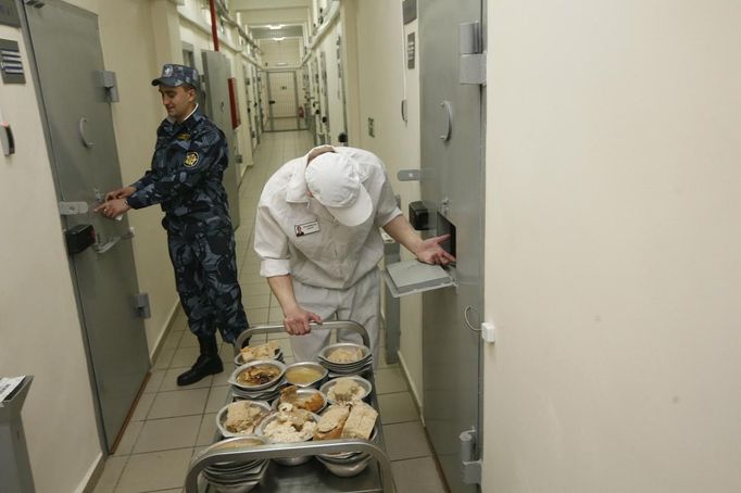 A security officer stands next to an inmate serving dinner to prisoners, inside a zone where especially strict conditions are imposed at a high-security male prison camp outside Russia's Siberian city of Krasnoyarsk May 14, 2013. High-security male prison camp number 17 is intended to house male inmates who are serving a sentence for the first time, and have been convicted for serious crimes. Prisoners at the facility work in wood and metal processing shops, manufacture furniture, sew clothes and do other kinds of work. They can also take part in educational, sport and cultural programs. Picture taken May 14, 2013. REUTERS/Ilya Naymushin (RUSSIA - Tags: CRIME LAW SOCIETY) ATTENTION EDITORS: PICTURE 12 OF 29 FOR PACKAGE 'INSIDE SIBERIA'S PRISONS' SEARCH 'ILYA PRISON' FOR ALL IMAGES Published: Čer. 19, 2013, 10:03 dop.