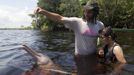 Igor Andrade (L), a physiotherapist, assists Alice Castro, 17 who suffers from mild cerebral palsy while interacting with a dolphin during a "Bototherapy" session at Arau River in Amazon August 11, 2012. The "Bototherapy", a "Rolfing" therapeutic practice assisted by river dolphins, was developed by Andrade and the treatment is free for children from low income with disabilities or disorders. Picture taken August 11, 2012. REUTERS/Bruno Kelly (BRAZIL - Tags: SOCIETY HEALTH) Published: Srp. 28, 2012, 12:16 dop.