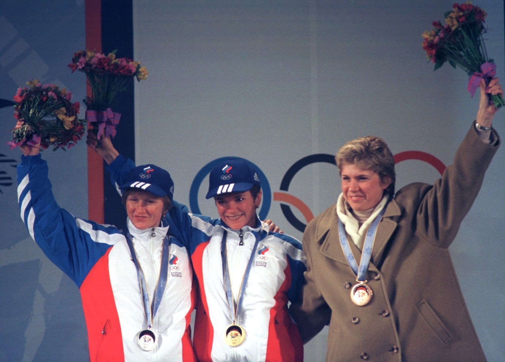 Kateřina Neumannová v kabátu na stupních vítězů na olympijských hrách v Naganu s Ruskami Larisou Lazutinovou a Olgou Danilovovou