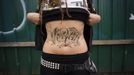 Mya Wollf, 28, a practising 'freegan' who has been vegan for nine years, shows off her 'vegan' tattoo in an alley behind Commercial Drive in Vancouver, British Columbia April 10, 2012. A 'Freegan' is someone who gathers edible food from the garbage bins of grocery stores or food stands that would otherwise have been thrown away. Freegans aim to spend little or no money purchasing food and other goods, not through financial need but to try to address issues of over-consumption and excess. Picture taken April 10, 2012. REUTERS/Ben Nelms (CANADA - Tags: SOCIETY) ATTENTION EDITORS PICTURE 01 OF 21 FOR PACKAGE 'DUMPSTER DIVING FOR FOOD' Published: Kvě. 15, 2012, 11:57 dop.