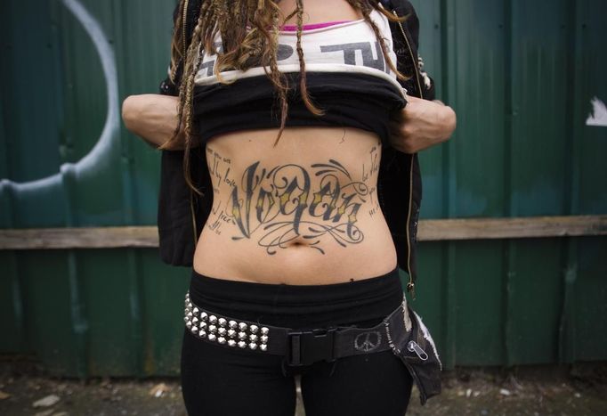 Mya Wollf, 28, a practising 'freegan' who has been vegan for nine years, shows off her 'vegan' tattoo in an alley behind Commercial Drive in Vancouver, British Columbia April 10, 2012. A 'Freegan' is someone who gathers edible food from the garbage bins of grocery stores or food stands that would otherwise have been thrown away. Freegans aim to spend little or no money purchasing food and other goods, not through financial need but to try to address issues of over-consumption and excess. Picture taken April 10, 2012. REUTERS/Ben Nelms (CANADA - Tags: SOCIETY) ATTENTION EDITORS PICTURE 01 OF 21 FOR PACKAGE 'DUMPSTER DIVING FOR FOOD' Published: Kvě. 15, 2012, 11:57 dop.