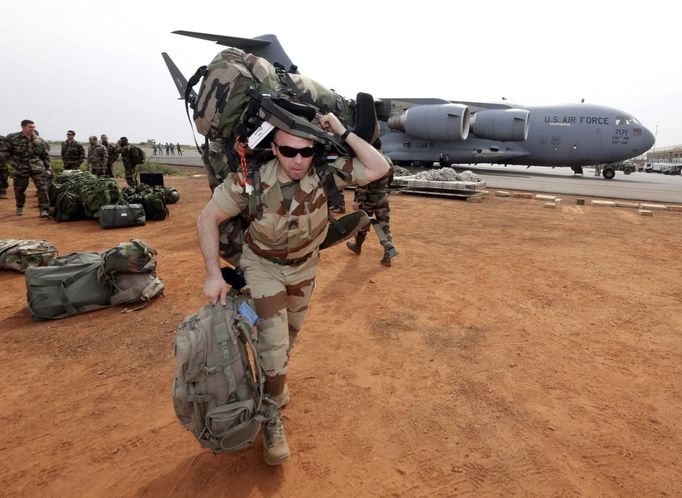 A French soldier carries his equipment after arriving on a US Air Force C-17 transport plane at the airport in Bamako January 22, 2013. The United States has started transporting French soldiers and equipment to Mali as part of its logistical aid to French forces fighting Islamist militants in the north of the country, a U.S. official said on Tuesday. REUTERS/Eric Gaillard (MALI - Tags: CIVIL UNREST CONFLICT MILITARY) Published: Led. 22, 2013, 4:20 odp.