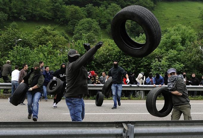 Miners on strike throw tires over a guardrail to build a barricade on the A-66 motorway, on the first day of a strike to protest the government's spending cuts in the mining sector, in Pola de Lena, near Oviedo, northern Spain, May 23, 2012. Spain's economy is contracting for the second time since late 2009 and four years of stagnation and recession have pushed unemployment above 24 percent, the highest rate in the European Union. REUTERS/Eloy Alonso (SPAIN - Tags: CIVIL UNREST BUSINESS EMPLOYMENT POLITICS) Published: Kvě. 23, 2012, 11:37 dop.