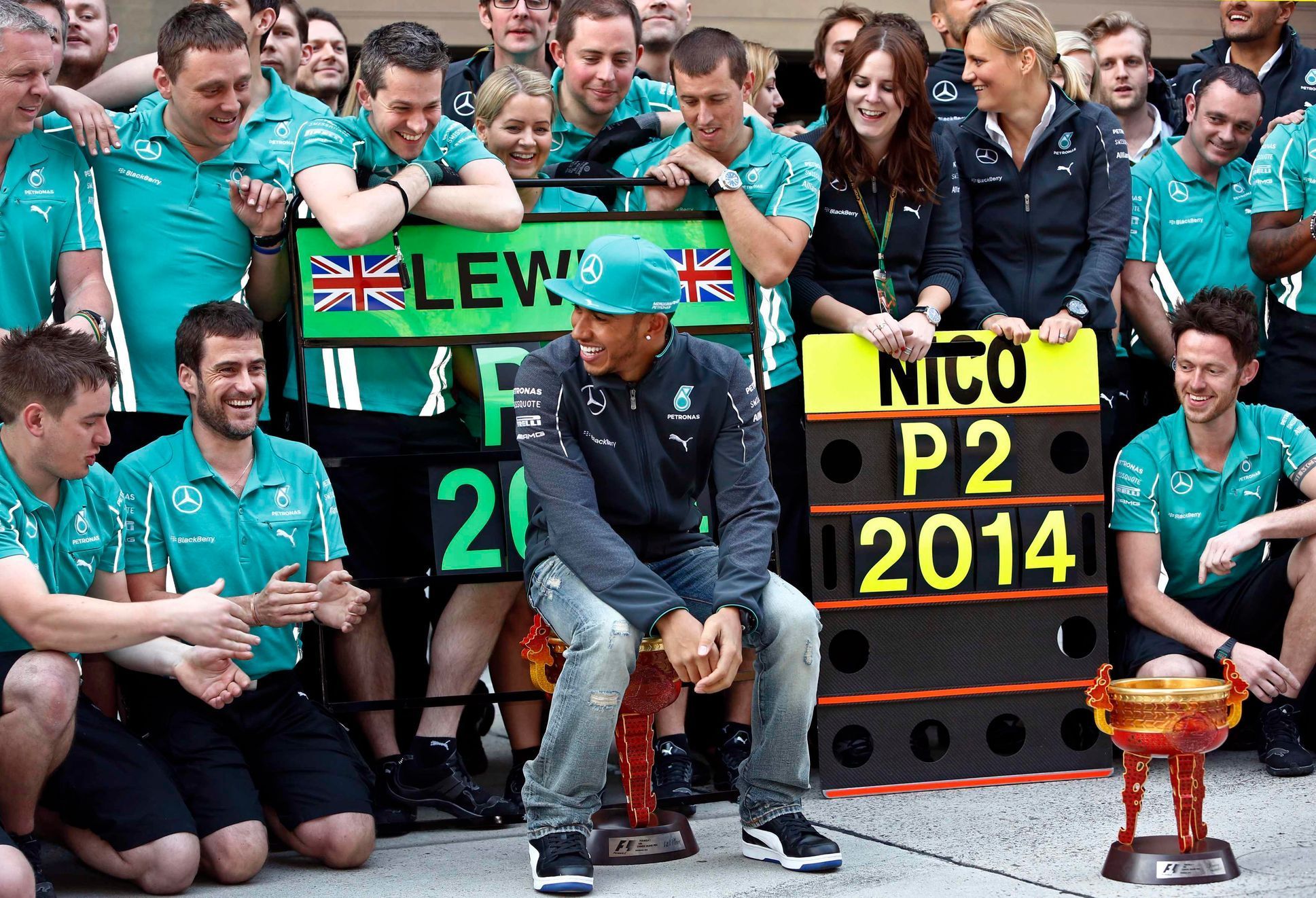 Mercedes Formula One driver Lewis Hamilton of Britain sits on his trophy as he celebrates with his team members during a photo call after winning Chinese F1 Grand Prix at Shanghai International circui
