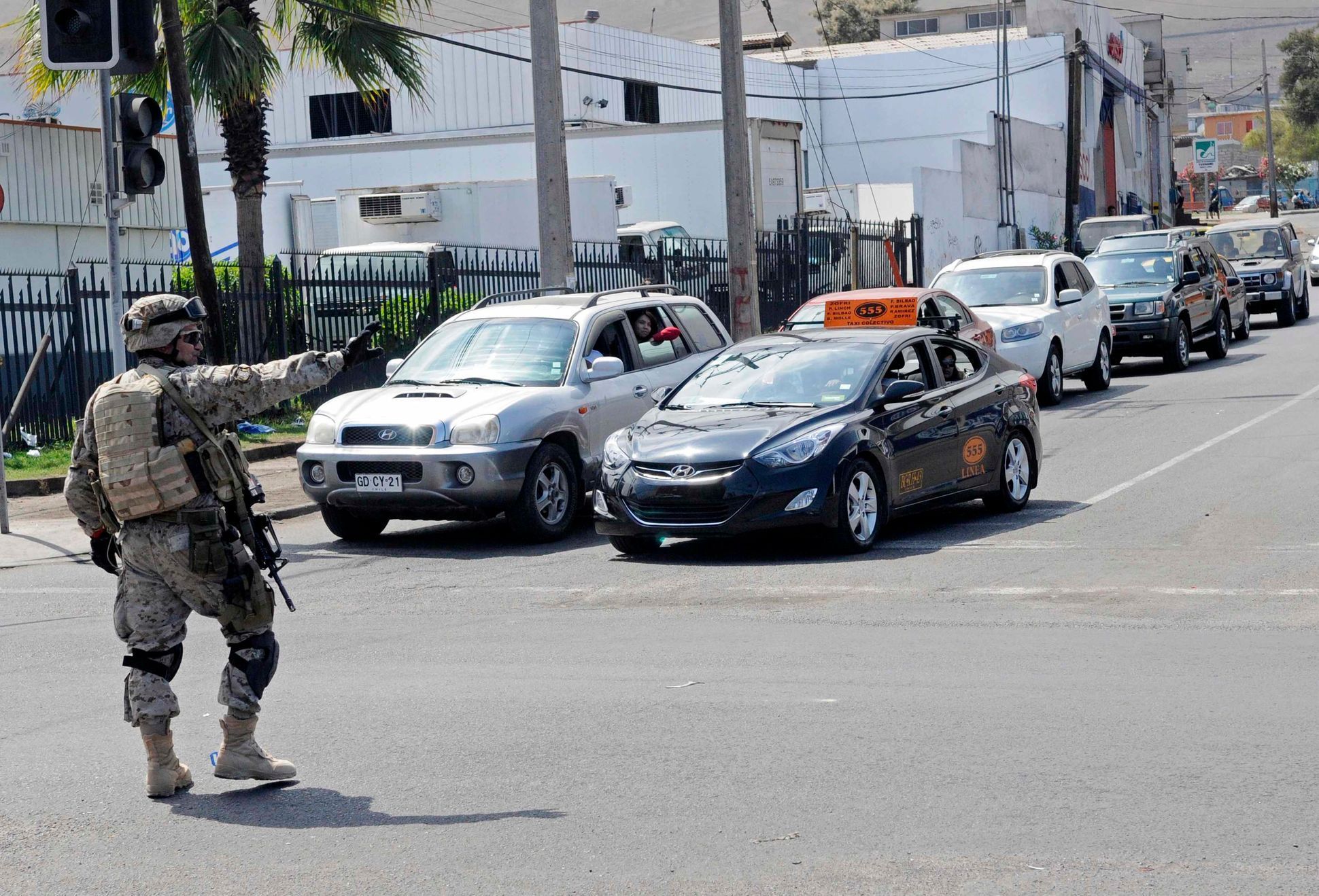 A soldier maintains order as dozens of cars lined up to buy fuel in Iquique