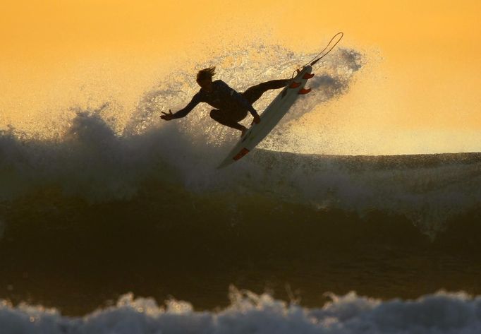 RNPS IMAGES OF THE YEAR 2012 - A young surfer sails his board off a wave as large swells hit the California coastline at dusk in Cardiff, California, January 5, 2012. REUTERS/Mike Blake (UNITED STATES - Tags: SOCIETY ENVIRONMENT SPORT TPX IMAGES OF THE DAY) Published: Pro. 5, 2012, 10:55 odp