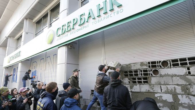 Ukrajinští nacionalisté zazdívají vchod do pobočky ruského Sberbanku v Kyjevě.