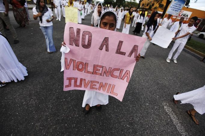 REFILE - ADDING INFO A devotee of the Light of the World Church holds a sign while participating in a march against violence in San Pedro Sula March 28, 2013. San Pedro Sula has been found to be the world's most violent city in 2012 for the second year running, with a rate of 169 homicides per 100,000 inhabitants -- an average of more than three people every day, according to a recent report published by the Mexican think tank Citizen Council for Public Security, Justice and Peace. The sign reads: "No to juvenile violence." REUTERS/Jorge Cabrera (HONDURAS - Tags: CRIME LAW CIVIL UNREST) Published: Bře. 29, 2013, 2:36 dop.