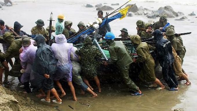 Vojáci a místní obyvatelé se snaží odtlačit uvízlou rybářskou bárku v Da Nangu ve středním Vietnamu, kudy se 1. listopadu přehnal tajfun Kai Tak.
