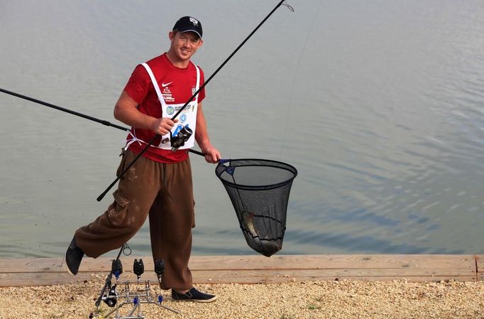 Mark Bartlett of England carries a carp he caught during the 14th Carpfishing World Championship in Corbu village, 310 km (192 miles) east of Bucharest, September 29, 2012. REUTERS/Radu Sigheti (ROMANIA - Tags: SOCIETY) Published: Zář. 29, 2012, 4:37 odp.