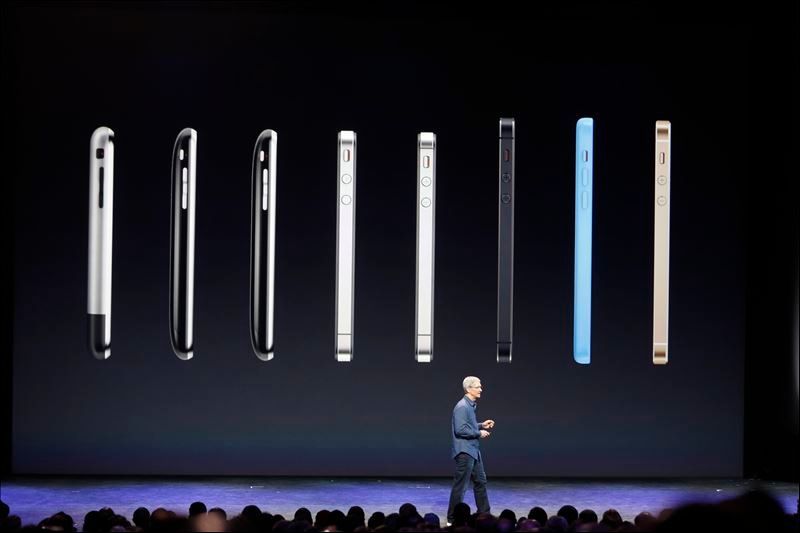 Apple CEO Tim Cook speaks in front of a row of iPhones during an Apple event at the Flint Center in Cupertino