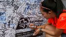 A woman writes on a wall dedicated to the passengers of the missing Malaysia Airlines flight MH370 before the Malaysian F1 Grand Prix at Sepang International Circuit outs