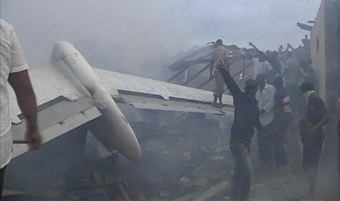 A still image taken from video shows emergency workers and volunteers around the wreckage of the tail of a plane that crashed in Lagos June 3, 2012. The passenger plane carrying nearly 150 people crashed into a densely populated part of Lagos on Sunday, in what looked like a major disaster in Nigeria's commercial hub. There was no early word from airline or civil aviation authority officials in the West African country on casualties. REUTERS/Stringer (NIGERIA - Tags: DISASTER TRANSPORT) Published: Čer. 3, 2012, 8:06 odp.