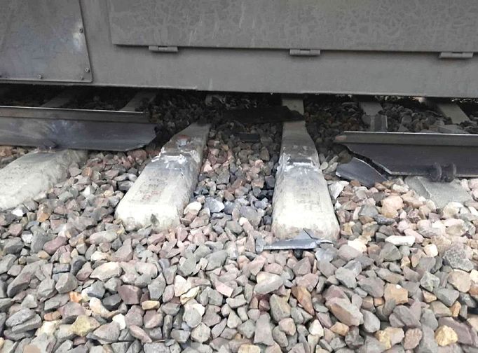 Poškozená železniční trať s roztříštěnými betonovými pražci a zdeformovaným úsekem ocelové kolejnice. Listopad 2025.