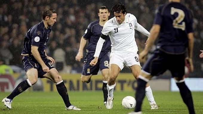 Italský kanonýr Luca Toni (v bílém) se mezi skotskými hráči napřahuje ke gólu v zápase kvalifikace ME.