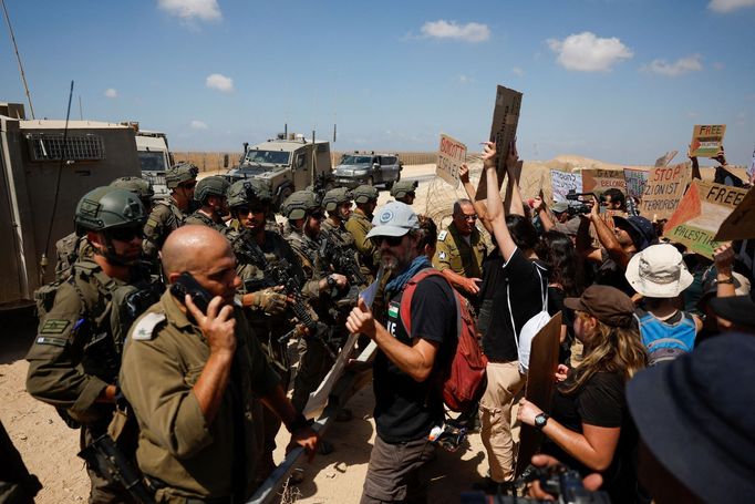 Izraelští vojáci stojí v pohotovosti, zatímco lidé protestují a vyzývají k ukončení konfliktu v Gaze mezi Izraelem a Hamásem u hranice Izrael–Gaza.