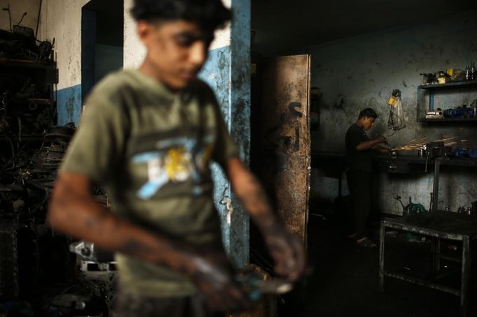 Palestinian Abed al-Majeed Reheem (R), 18, works in a car repair garage in Gaza City May 30, 2013. Reheem left school to work as an apprentice in the garage so that he could support his family's income. Apprentice mechanics earn around $100 per month, garage owners said. REUTERS/Mohammed Salem (GAZA - Tags: TRANSPORT SOCIETY EMPLOYMENT) Published: Kvě. 30, 2013, 12:54 odp.