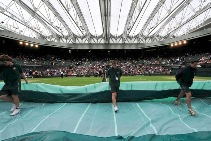 Pořadatelé odklízejí plachtu před utkáním Juana Martína Del Potra a Davida Ferrera v osmifinále Wimbledonu 2012.